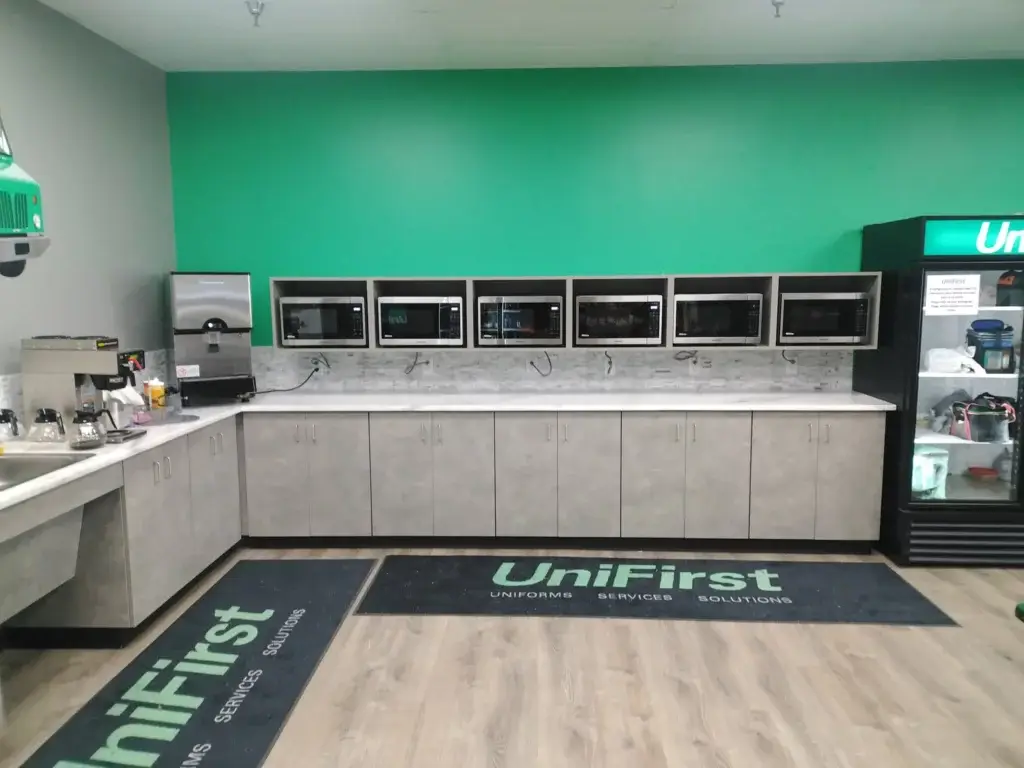 Gray plastic laminate casework with solid surface tops and floating microwave cabinets for break room.