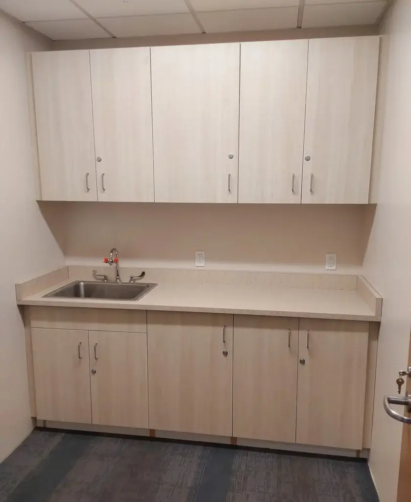 Wood grain plastic laminate base and wall cabinets with sink and locks.