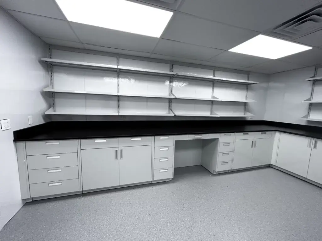 Laboratory space with base cabinet run and upper open wall shelves.