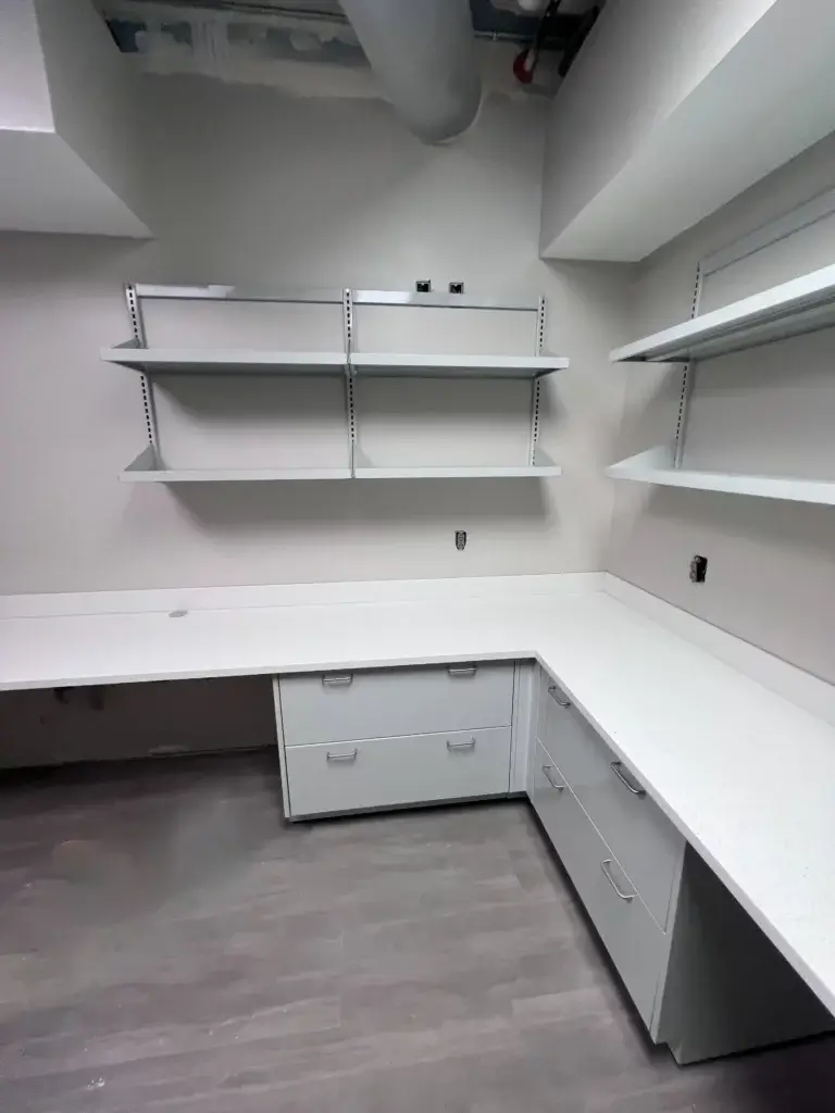 L-Shaped lab furniture set up with white metal cabinets, removable shelving and chemical resistant countertops