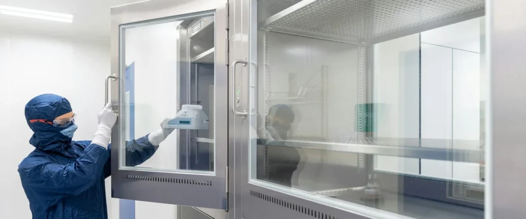 Modern stainless steel ventilated containment enclosure with pharmaceutical technician opening the sash, demonstrating sash management on a SEFA 1 fume hood installation