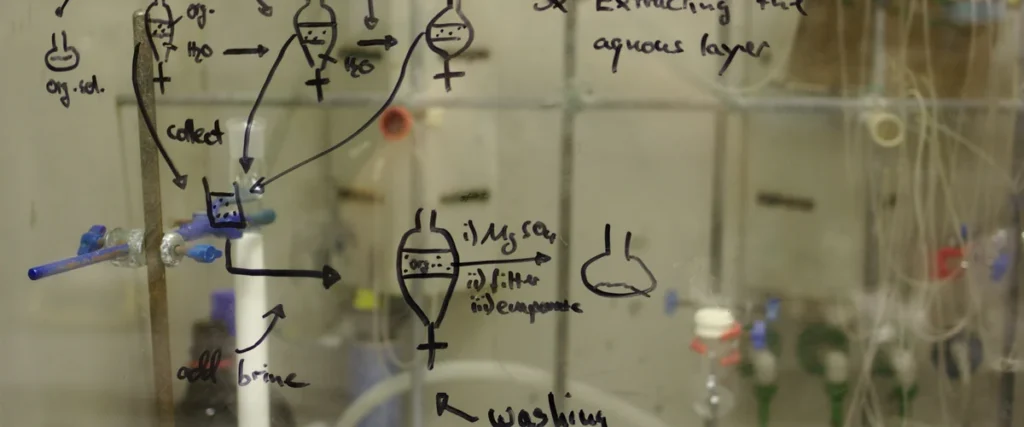 Chemistry fume hood sash glass with reaction work-up sketched in marker