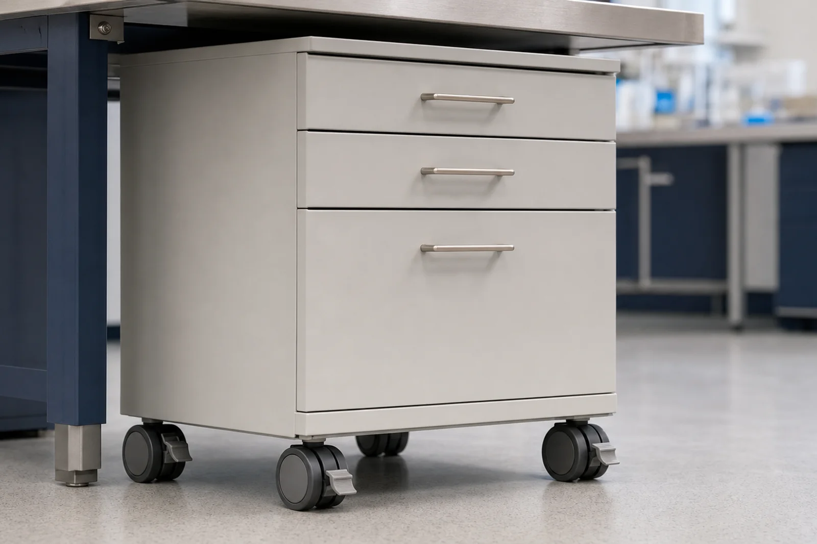 Close-up of a laboratory mobile base cabinet on three-inch double-wheel locking casters slotted under an adjustable height work bench